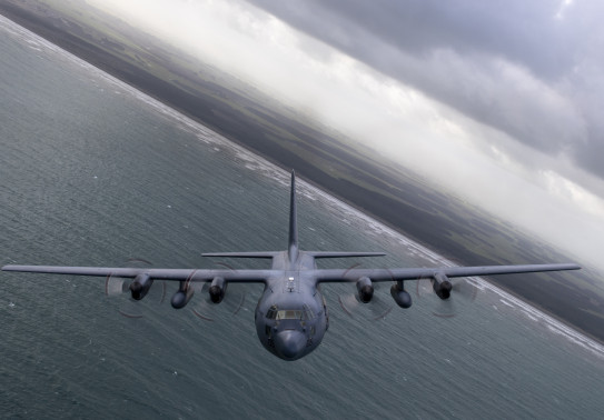 A C-130H(NZ) Hercules banking while flying over ocean.