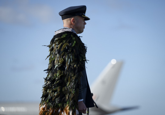 An aviator stands in uniform looking away from the camera. 