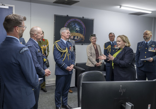 Senior aviators talk to the Minister for Space in a control room.
