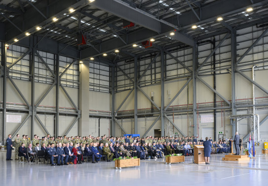 A crowd of people seated in a large aircraft hangar.