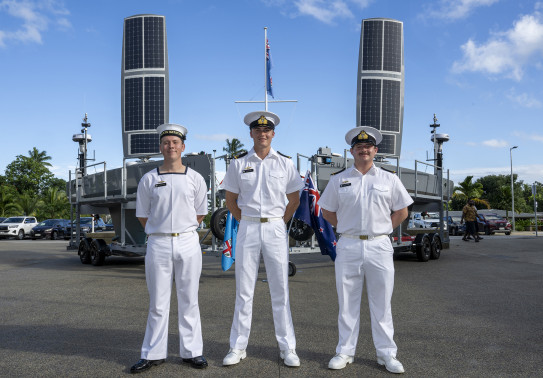Three sailors stand in a row in uniform, hands behind their backs