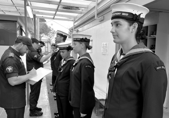 Navy recruits stand in a line as they have their uniform inspected during the Basic Common Training course.