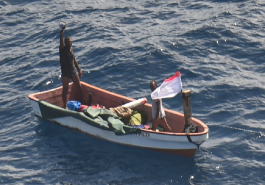 Two people on a small boat who went missing in Kiribati waters waving to camera (on aircraft)  RNZAF P-3K2 Orion following a two-day search.