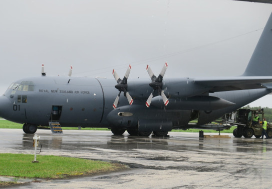 A Royal New Zealand Hercules aircraft on the tarmac at the airport in Tonga. Air Force personnel are removing supplies from the aircraft