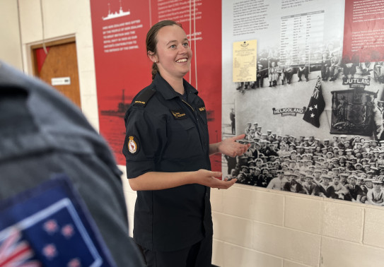 Woman smiles as she stands in front of a sign.