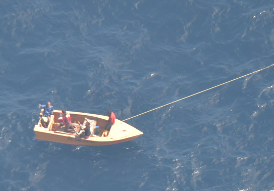 An aerial photo of a small boat with off Kiribati with three men on board.