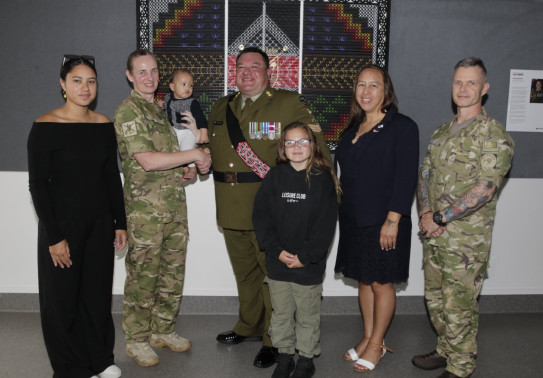 A group photo of three soldiers and two civilian adults, a child and a baby.